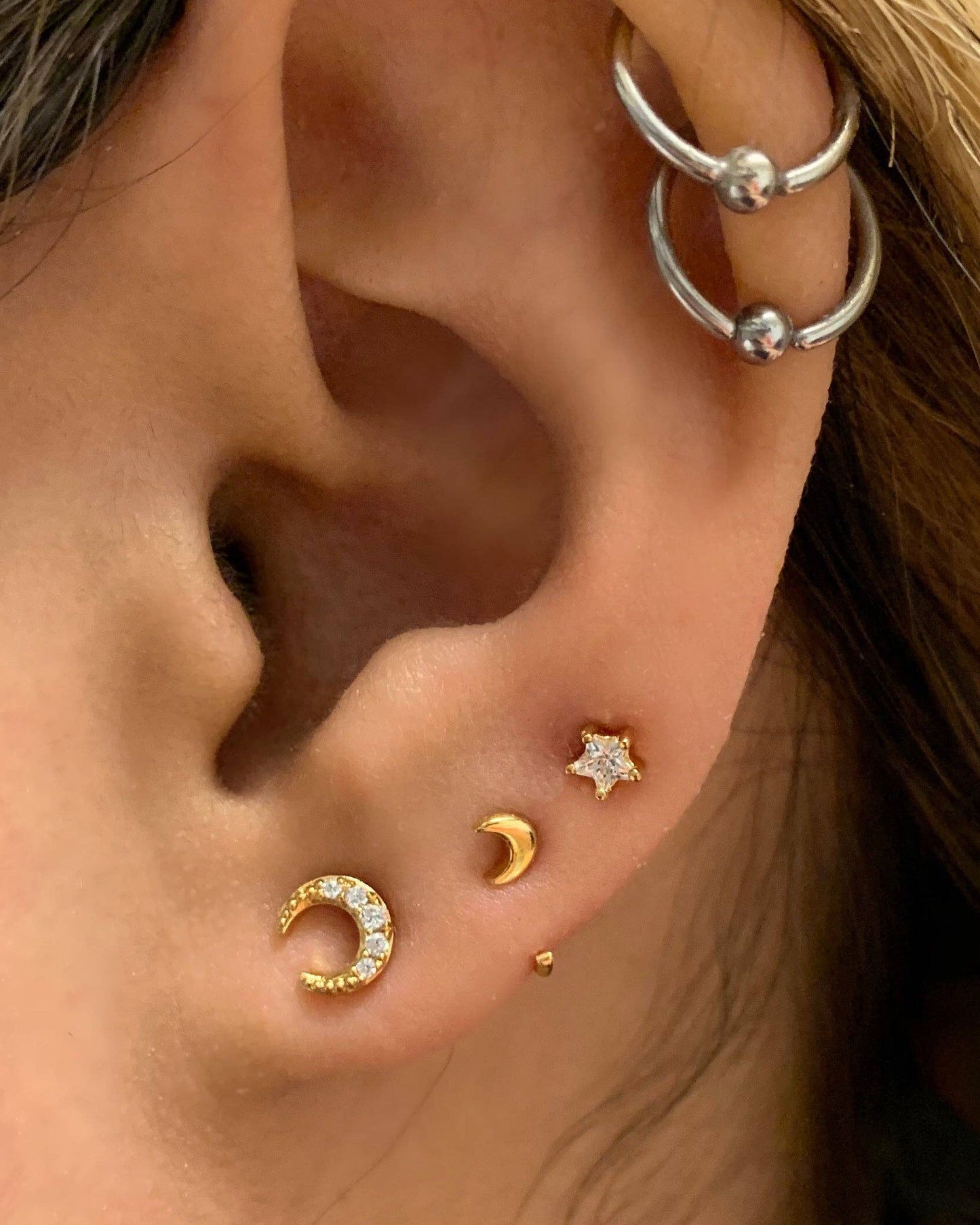 Close-up of an ear with gold and silver earrings.