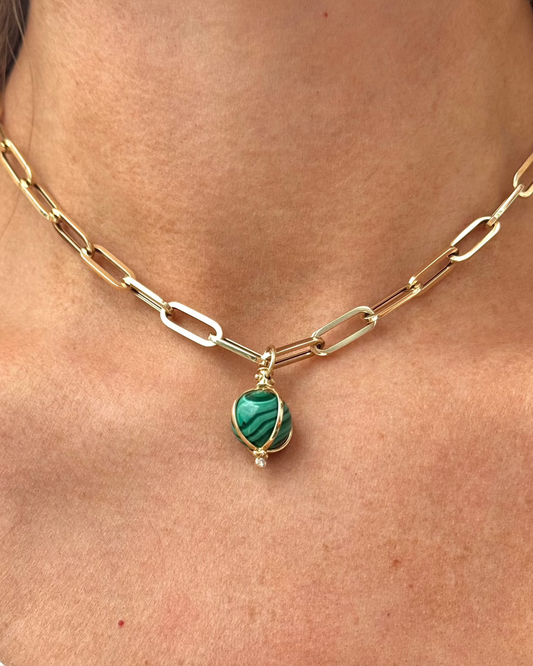 Close-up of a gold chain necklace with oblong links, featuring the ZENDA Malachite Necklace by Dylan James Jewelry, made of green malachite wrapped in 14kt yellow gold and adorned with a small diamond.