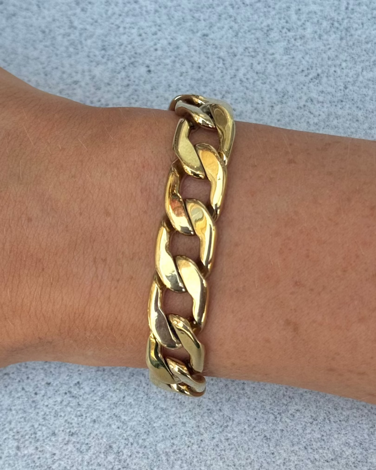 A gold link bracelet on a wrist, with a focus on the bracelet's gold-filled bands and links.