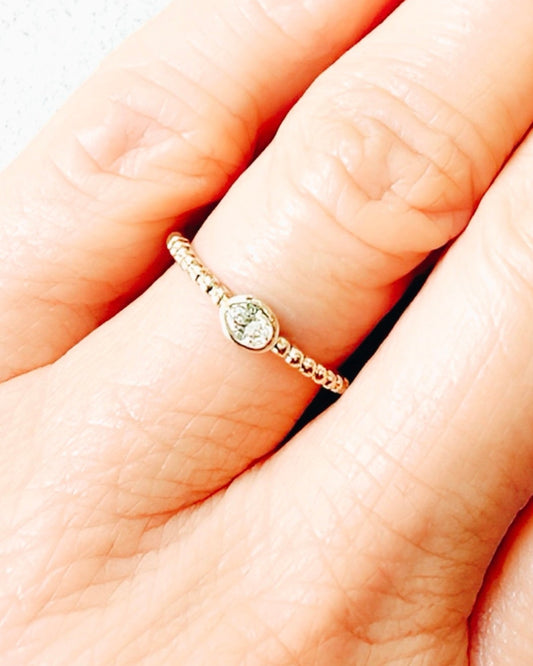 Gold ring with a small gemstone on a hand against a white background