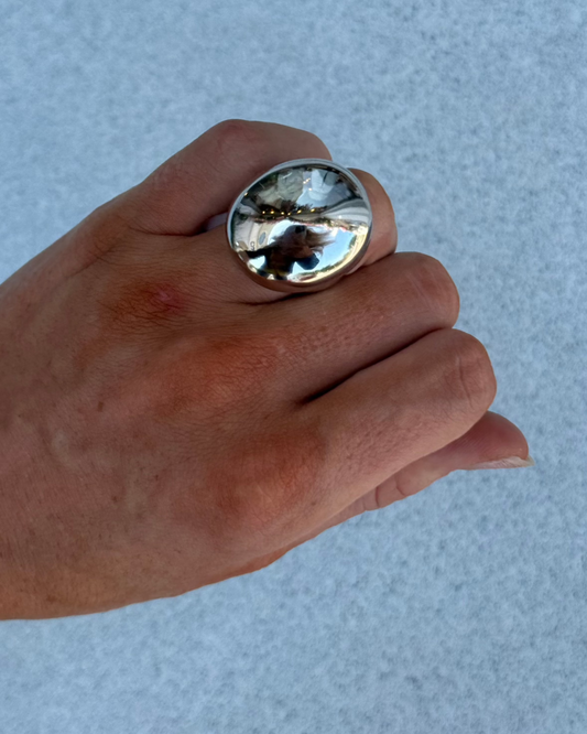 A hand showcases the NOAH Silver Chunky Ring by Dylan James Jewelry against a light blue textured background.