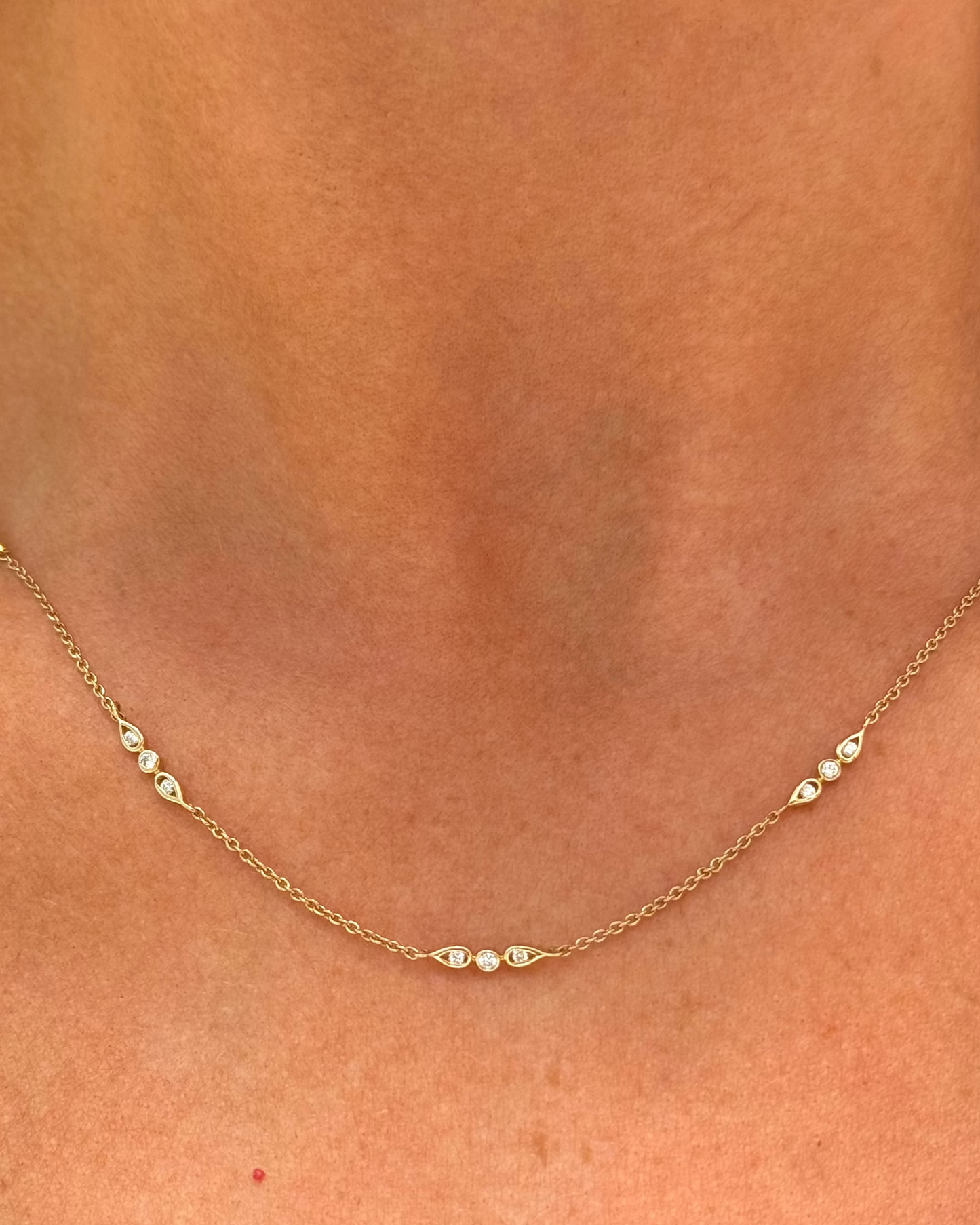 Close-up of the Dylan James Jewelry Ray Diamond Necklace, a delicate 14kt yellow gold piece adorned with evenly spaced diamonds, elegantly worn around a person's neck.