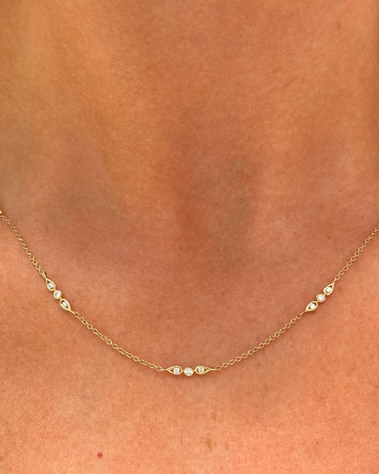Close-up of the Dylan James Jewelry Ray Diamond Necklace, a delicate 14kt yellow gold piece adorned with evenly spaced diamonds, elegantly worn around a person's neck.