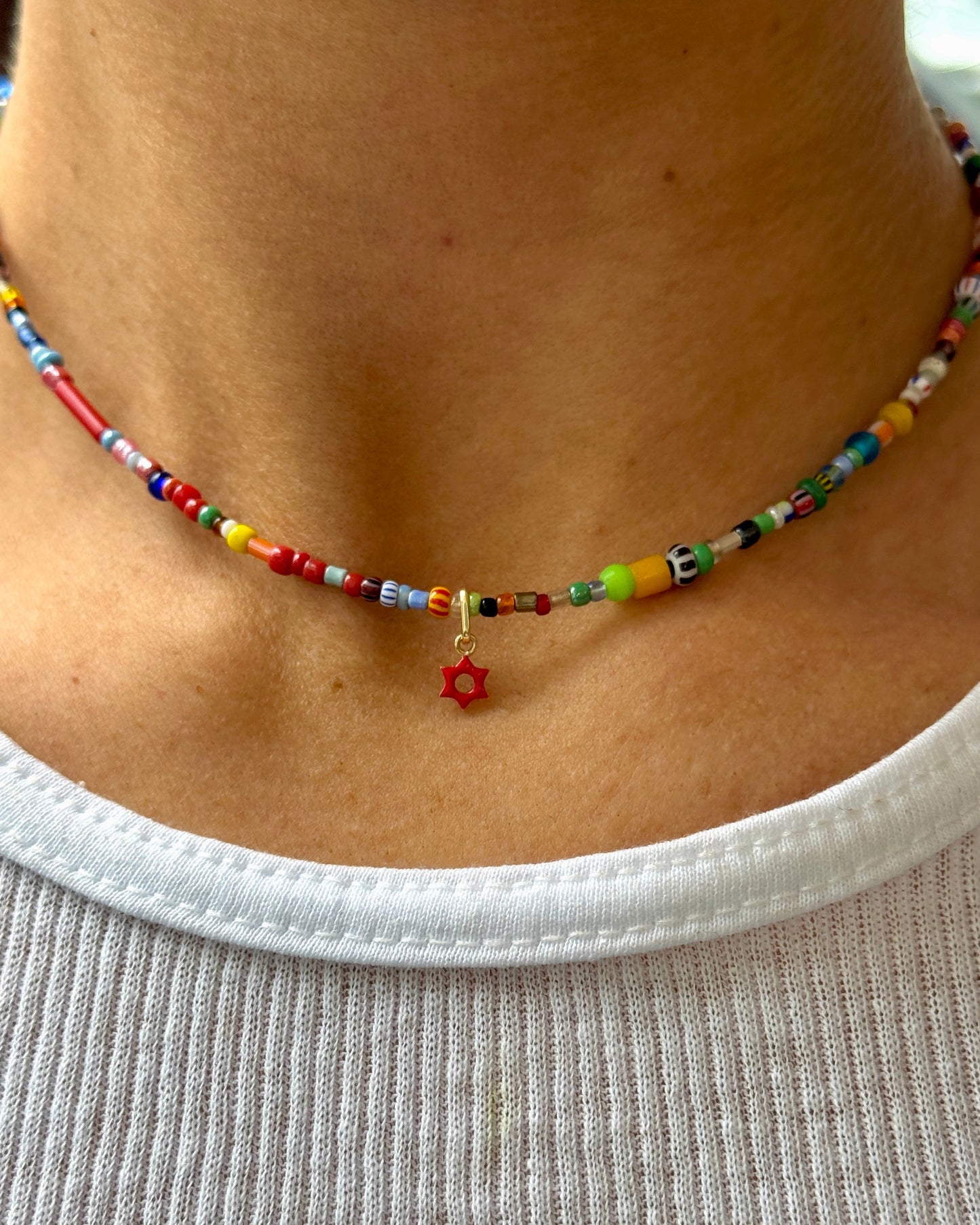 Colorful beaded necklace with a star charm worn by a person on a plain background