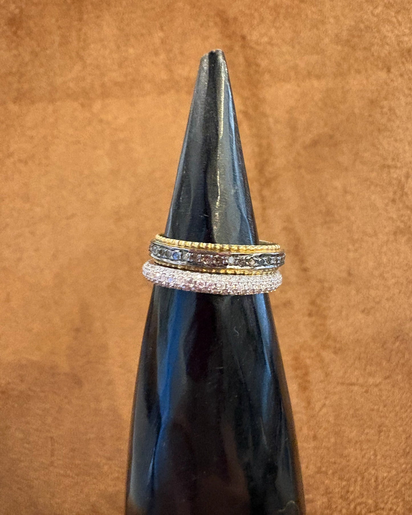Three rings stacked on a black bottle against a brown background