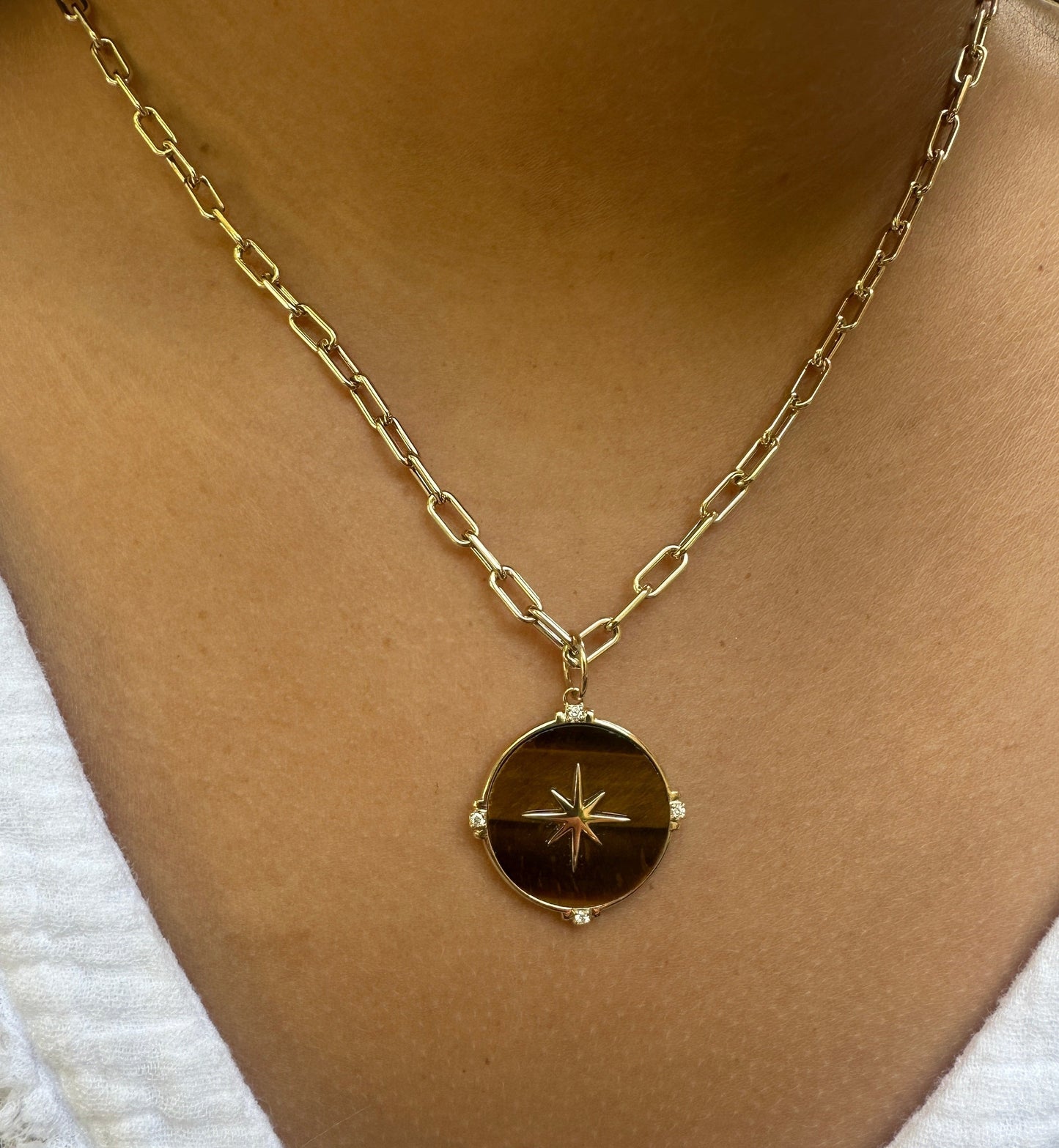 The ANNIE Gold Chain by AIRA, a 16" yellow gold link chain with an extender, elegantly drapes around the neck. Its circular pendant features a star design for celestial charm. The 8mm x 3mm links balance bold style with sophistication.