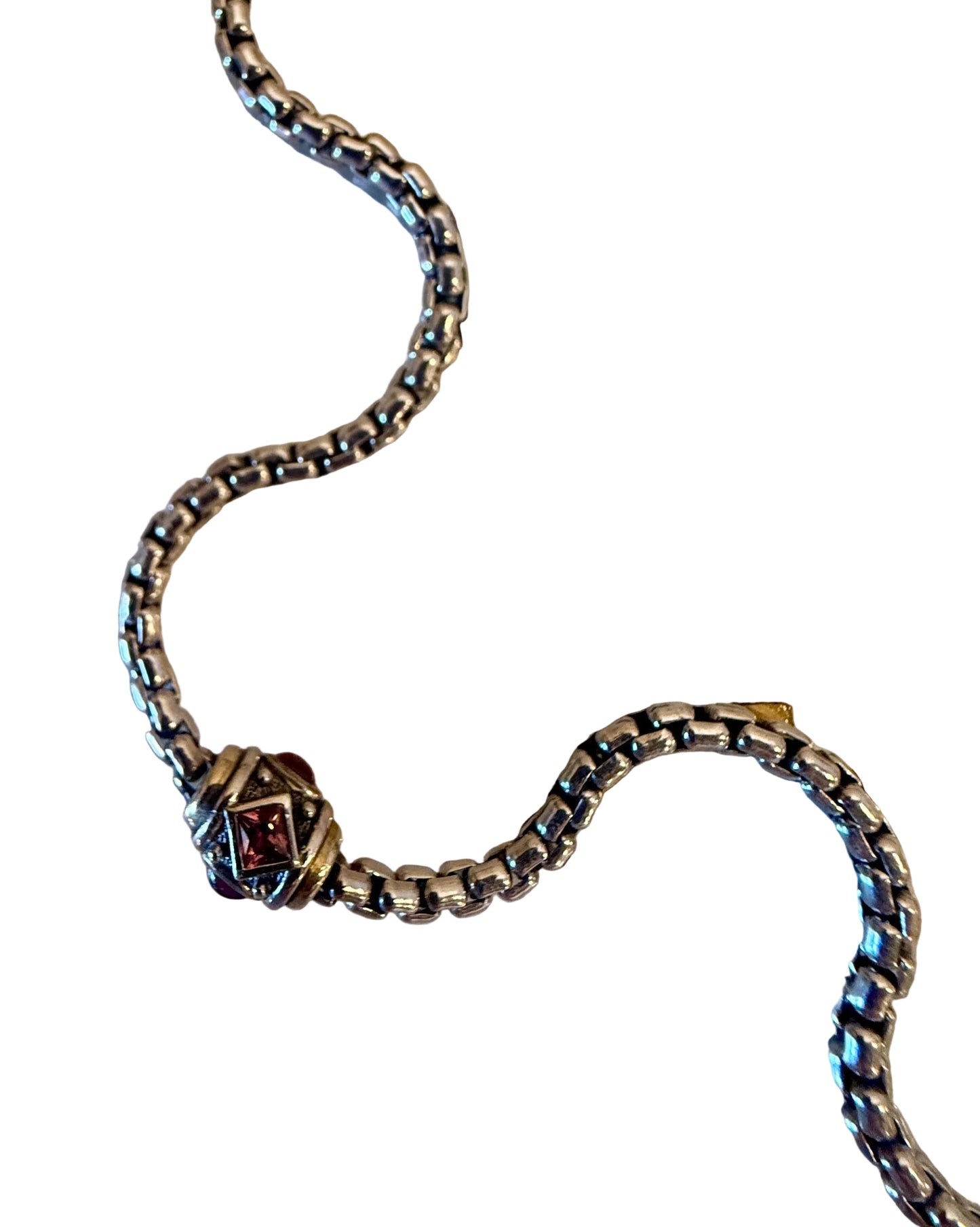 Silver chain with a clasp on a white card with measurement markings