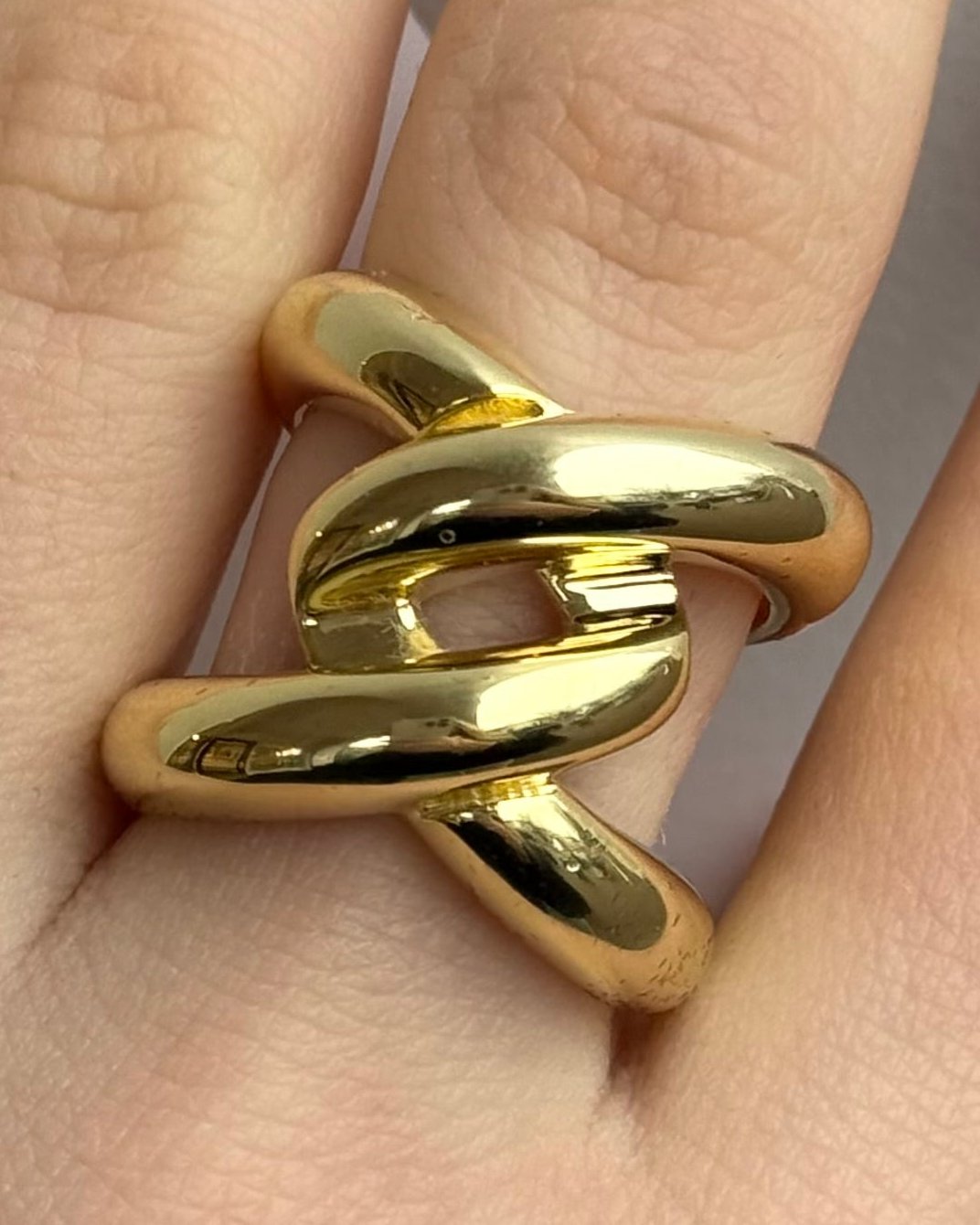 The Harry Ring by Dylan James Jewelry, featuring a gold-plated intertwined knot design, fits elegantly on a size 7 finger.