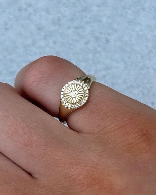 The SUNNY Ring by Dylan James Jewelry, crafted in 14kt gold with a sunburst design, elegantly adorns the finger and glistens under the light.