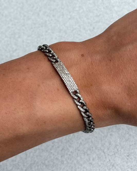 The AYZ Bracelet by Dylan James Jewelry, crafted from sterling silver, elegantly adorns a person's wrist and glimmers against a light gray background.