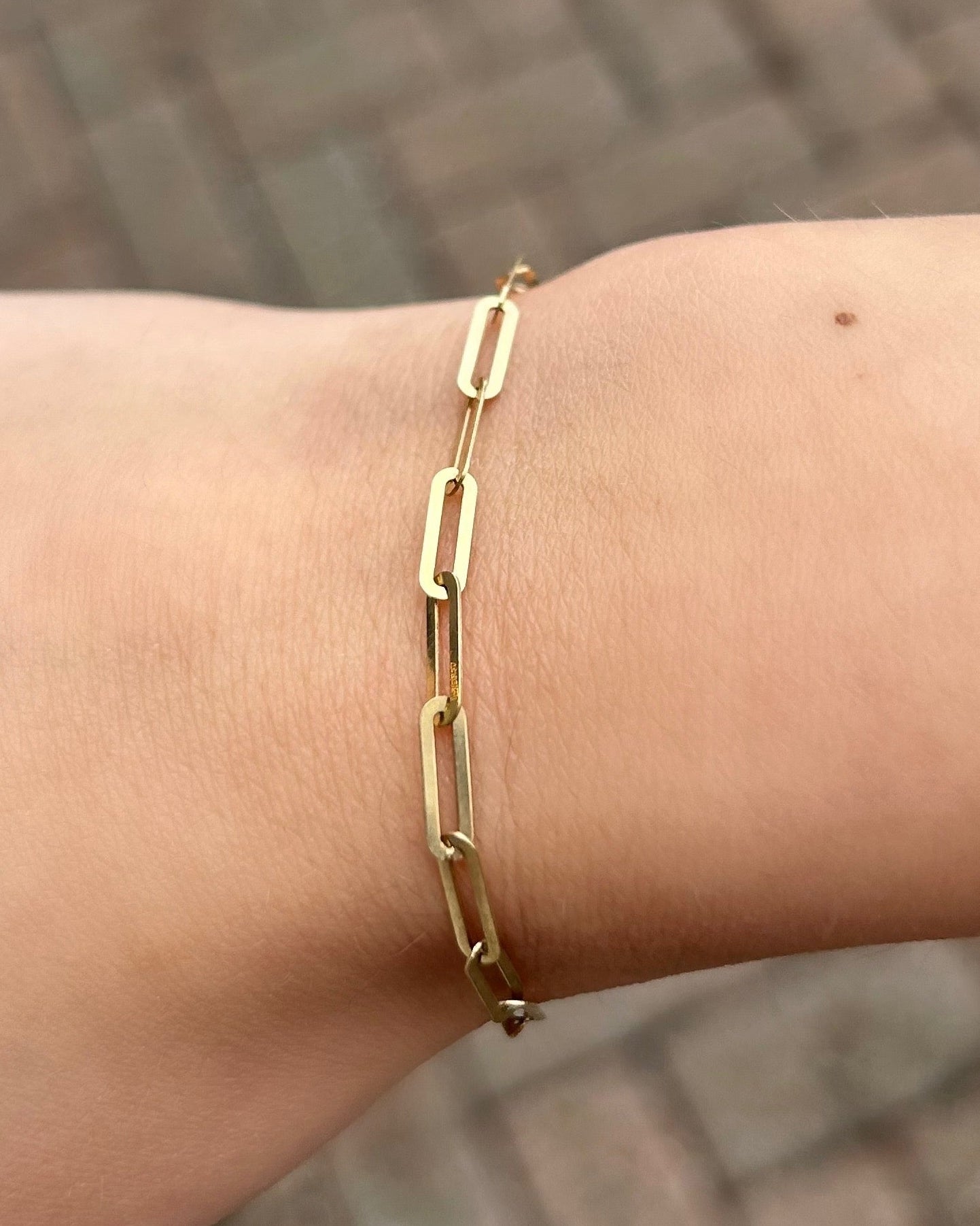 Gold bracelet on a wrist with a blurred background