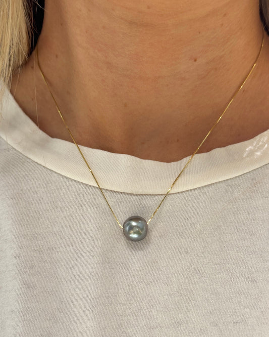 Necklace with a single pearl pendant on a plain background
