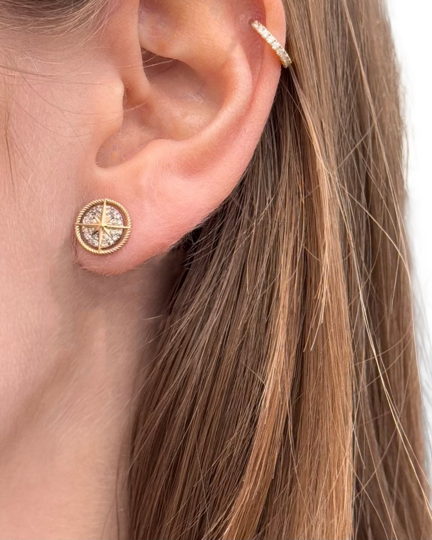 Close-up of a woman's ear wearing Dylan James Jewelry's COMPASS Silver Diamond Studs and a small gold hoop cuff on the upper ear.