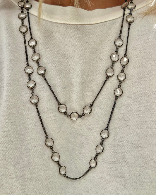 Two layered necklaces with clear beads on a plain background