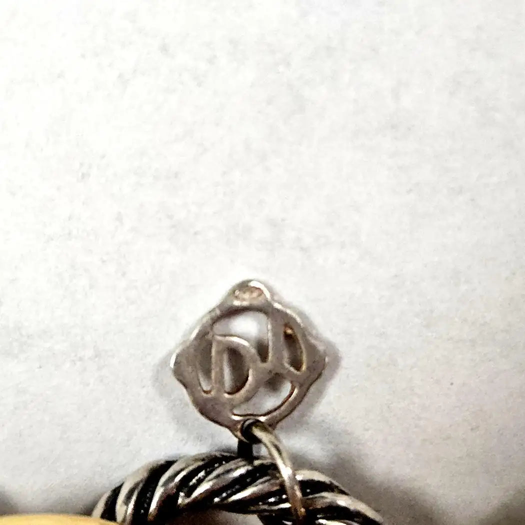 Close-up of a silver pendant with a logo on a white background