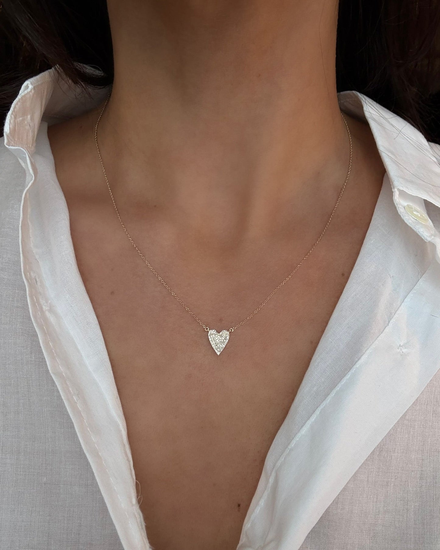 Heart-shaped necklace worn by a person with a white shirt