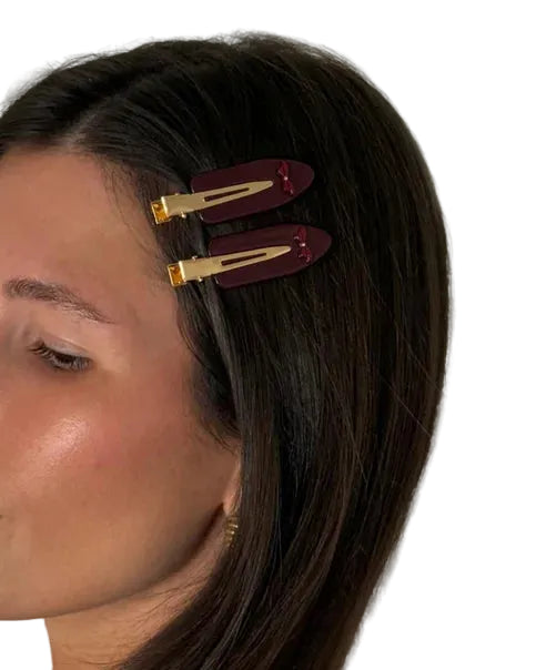 Woman with hair styled using red hair clips on a neutral background