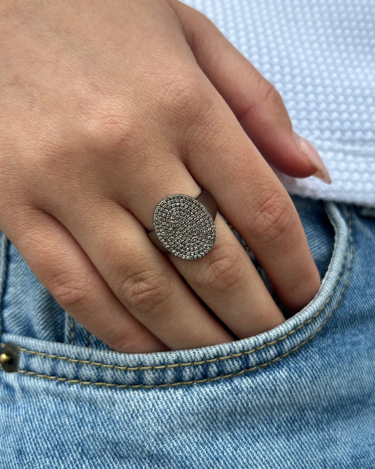 A hand wearing the Dylan James LINDA Sterling Diamond Ring, adorned with sparkling stones, rests on the edge of a denim pocket.