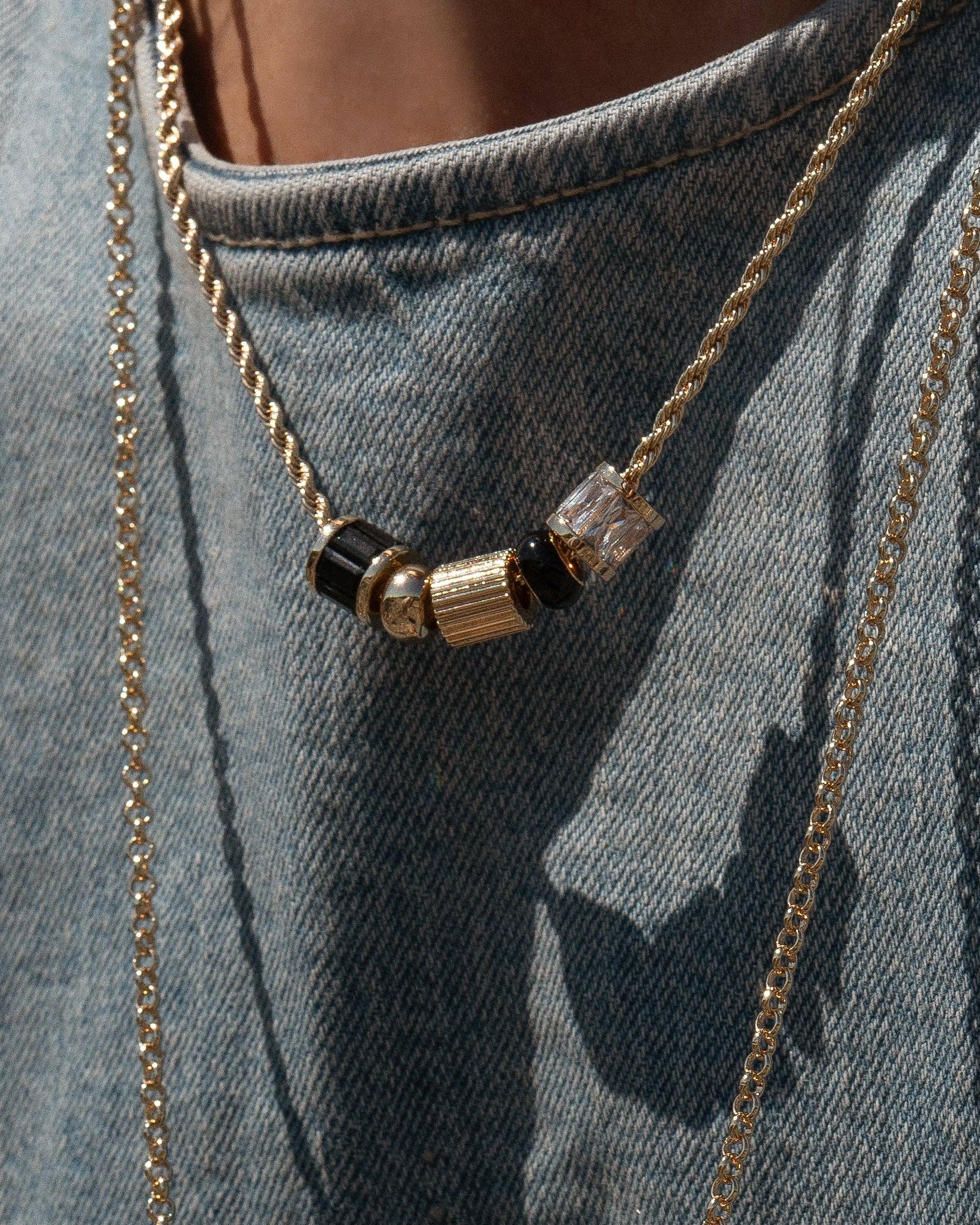 Necklace with black and gold beads on a denim background
