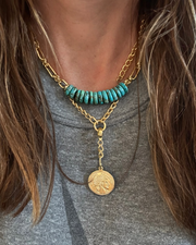 Necklace with turquoise beads and gold coins on a gray shirt