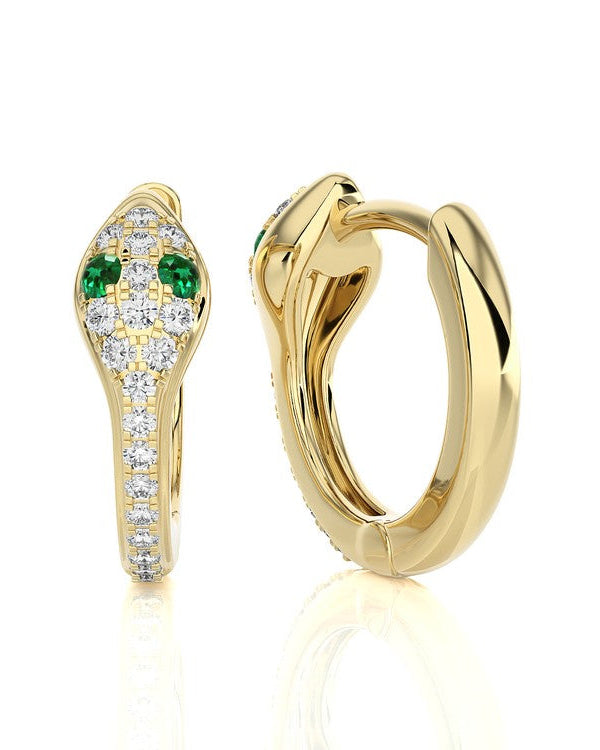 A pair of gold huggie hoop earrings with a snake-head design, featuring green emerald-cut stones and pavé-set clear stones, shown on a white background with a soft reflection.