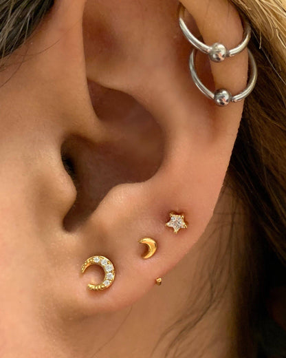 Close-up of an ear with gold and silver earrings.