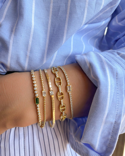 Close-up of a wrist wearing multiple gold bracelets with a blue shirt in the background