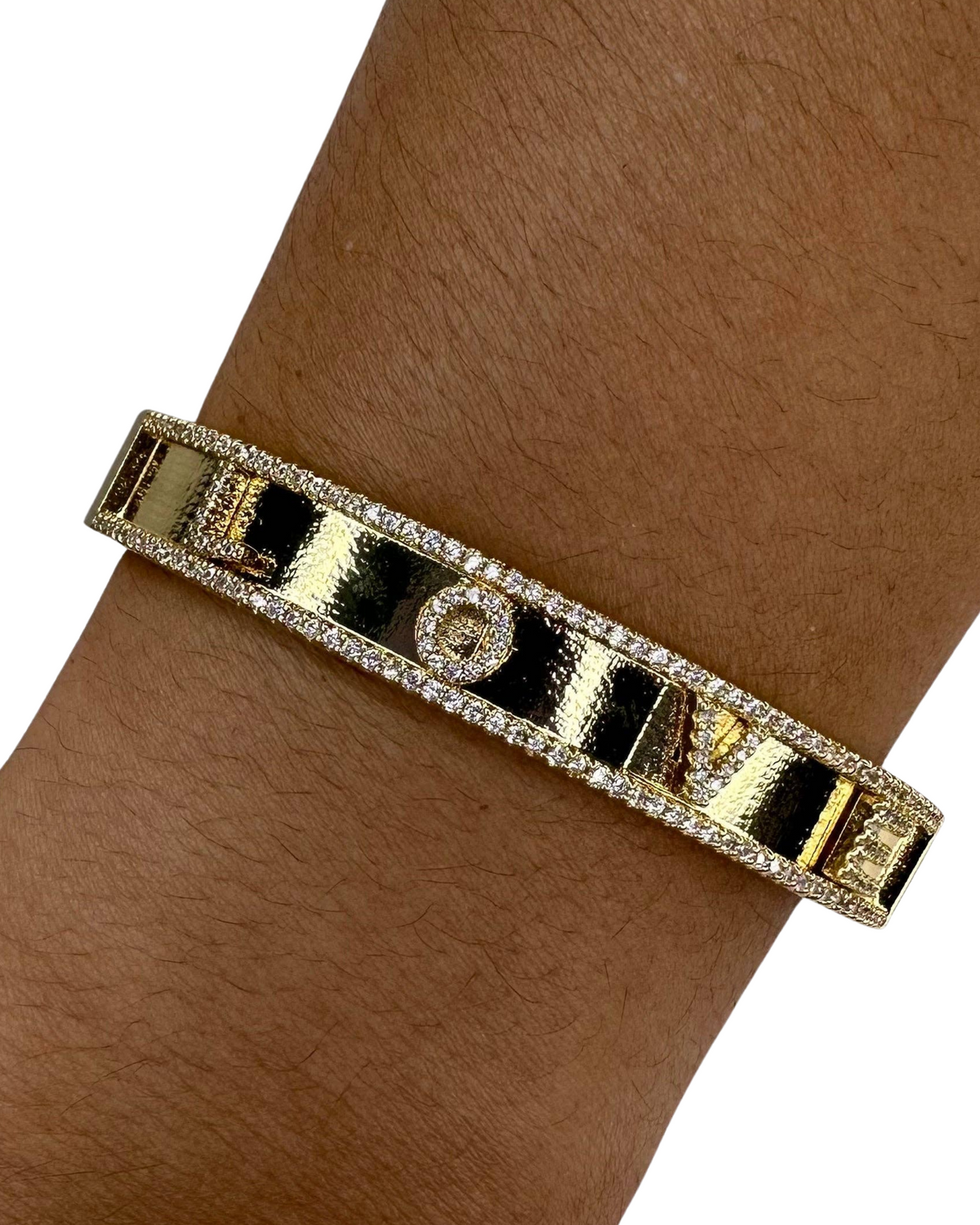 Gold bracelet with black accents on a wrist against a white background