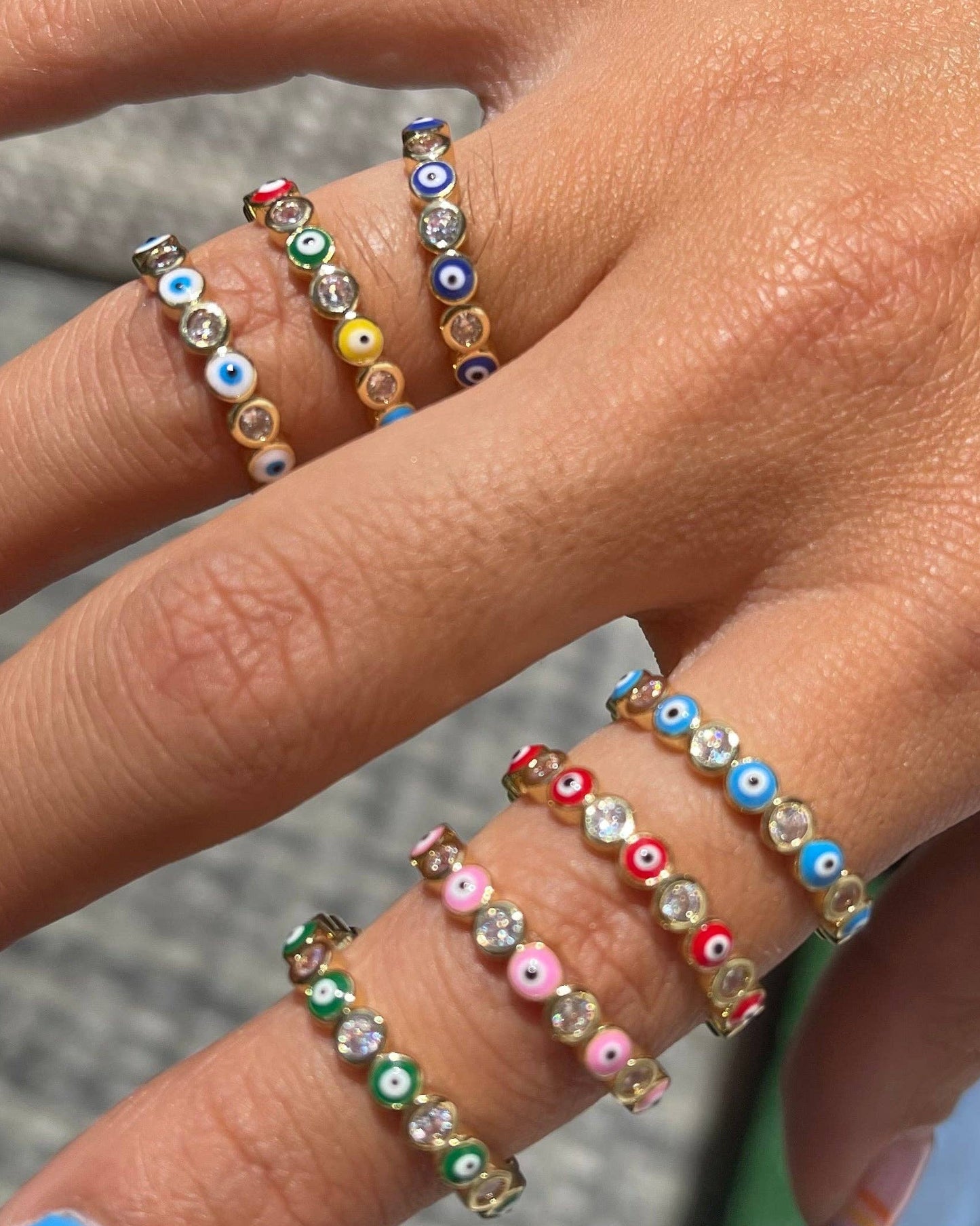 Close-up of a hand wearing colorful beaded rings with a blurred background