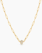 Gold necklace with a small round pendant on a white background