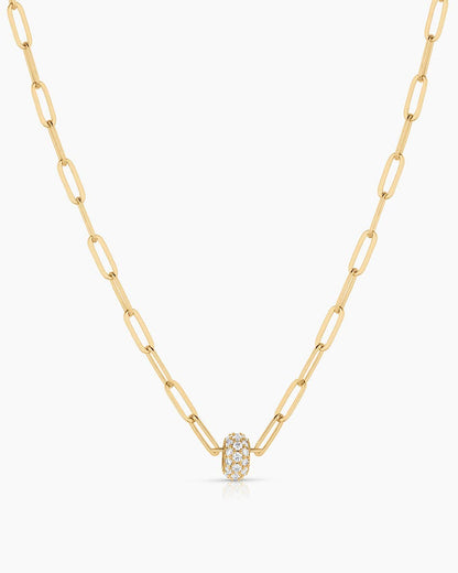 Gold necklace with a small round pendant on a white background