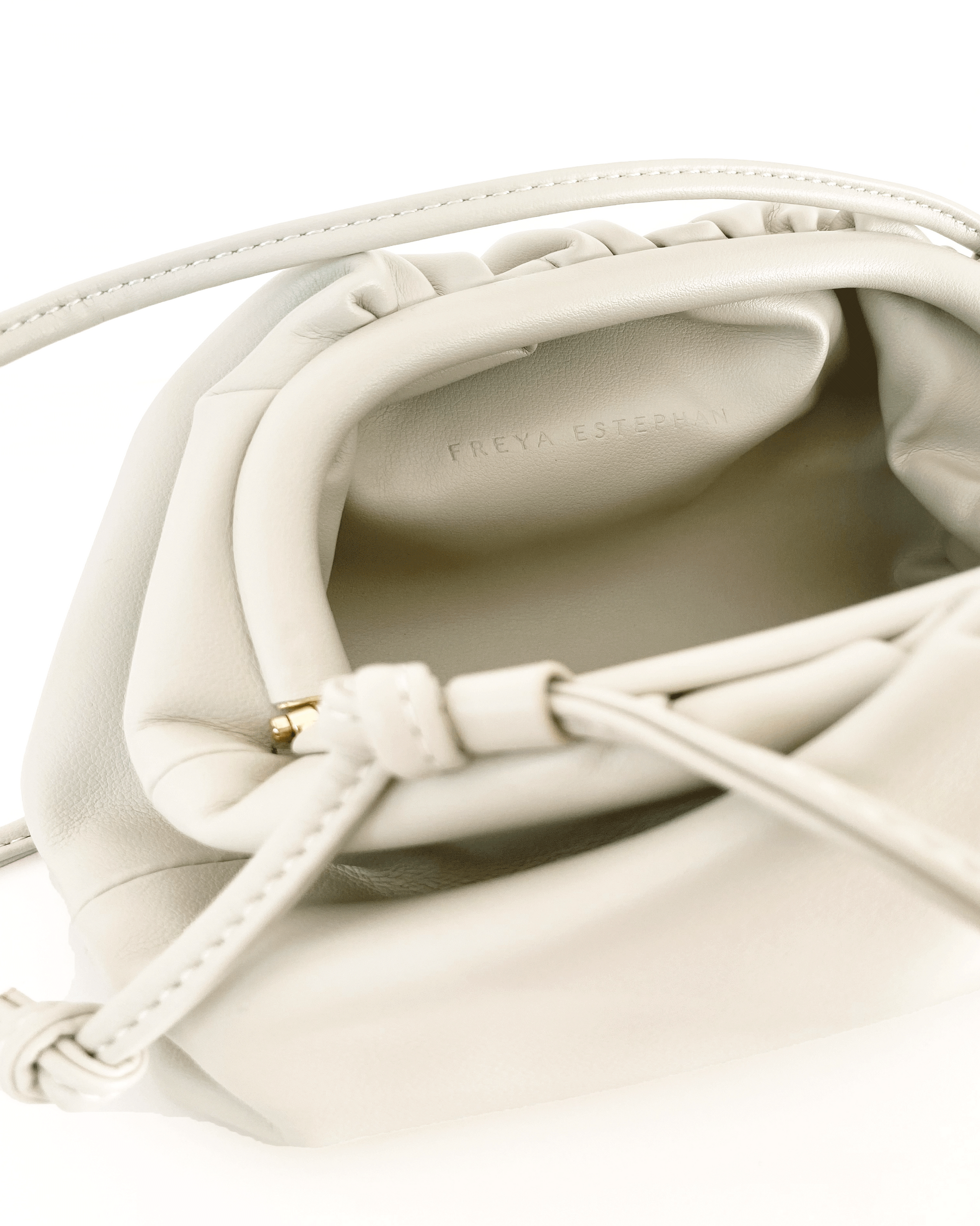 Close-up of a white leather handbag with braided handle on a white background