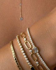 Gold jewelry set including a necklace and bracelets on a person's arm.