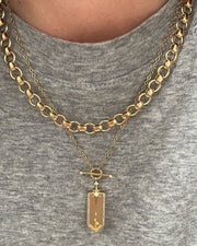 Gold chain necklace with a pendant on a gray shirt