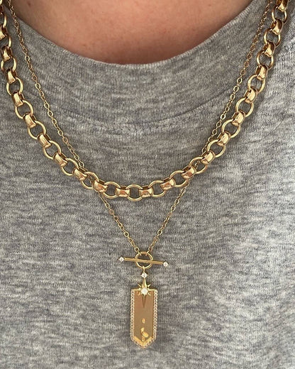 Gold chain necklace with a pendant on a gray shirt