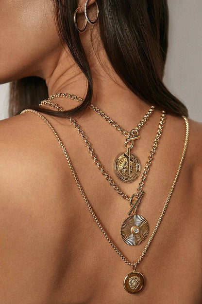 Close-up of a woman wearing multiple gold necklaces with intricate designs.