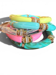 A stack of colorful bangle bracelets with gold-toned spacer rings, featuring translucent clear, pink, turquoise, mint green, and neon yellow segments.
