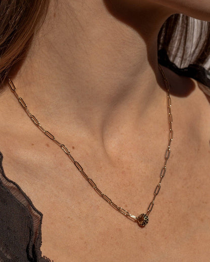 Necklace with a small pendant worn by a person against a neutral background