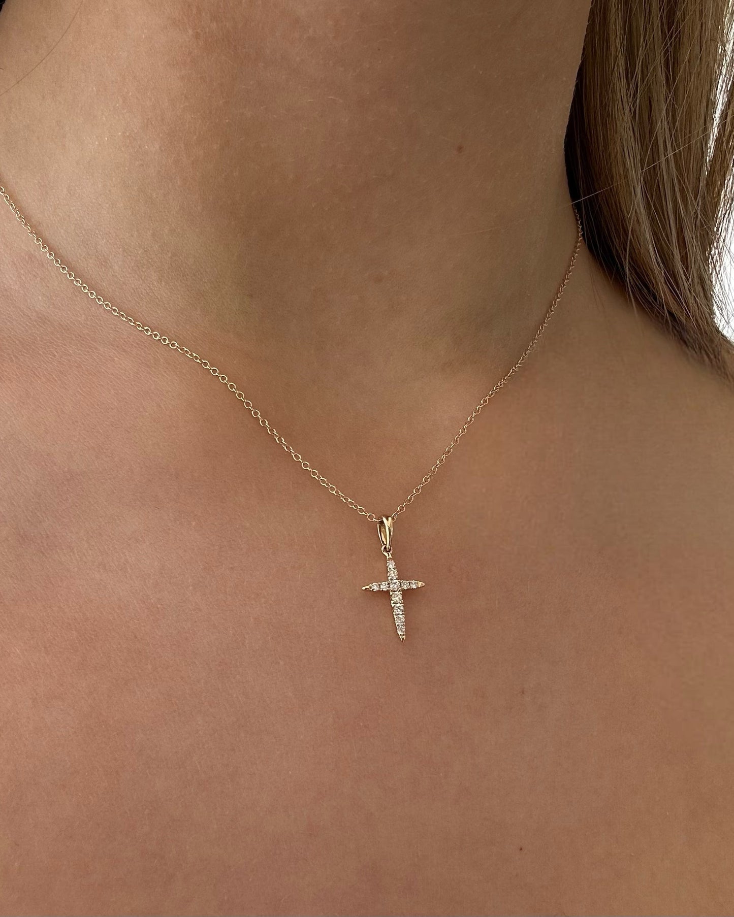 Gold necklace with a cross pendant on a person's neck