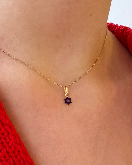 Gold necklace with a purple gemstone pendant on a person wearing a red garment.