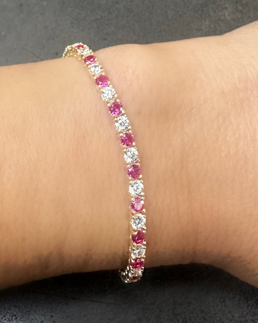 The GEORGE Tennis Bracelet by Dylan James Jewelry features a luxurious gold-plated design with alternating pink and clear cubic zirconia gemstones that beautifully adorn the wrist.
