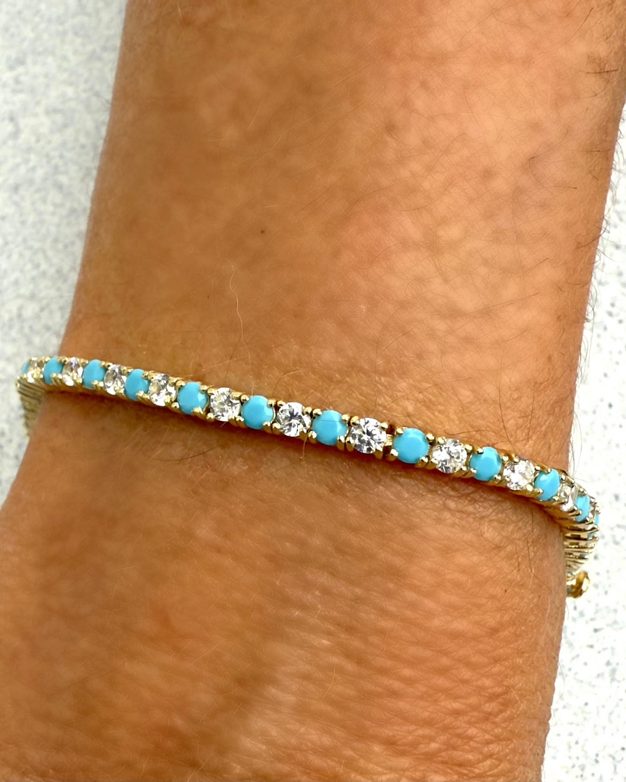 The HELENA Turquoise Tennis Bracelet by Dylan James Jewelry features gold-plated sterling silver with alternating turquoise and cubic zirconia stones, adding elegant style to your wrist.