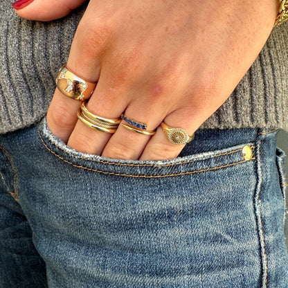 A hand adorned with Dylan James Jewelry's DEBBIE Diamond Ring rests in the front pocket of blue jeans. A sparkling diamond-studded bracelet glints on the wrist beneath the gray sweater sleeve.