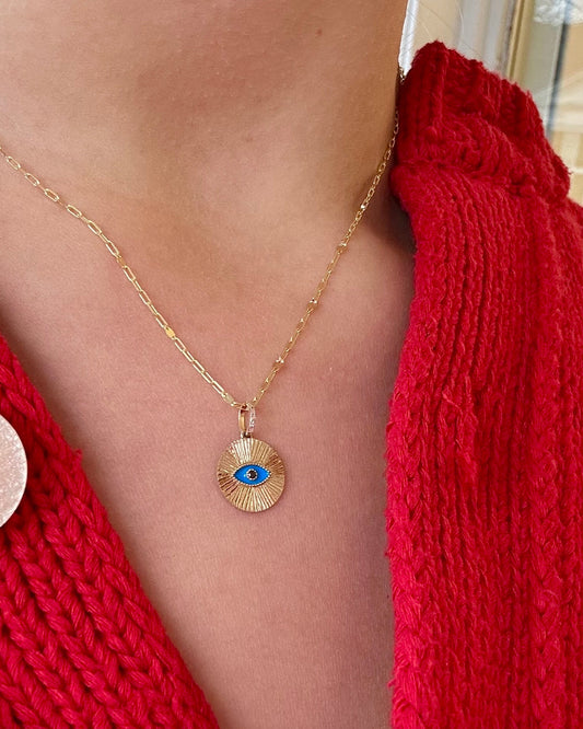 Necklace with a pendant worn by a person in a red knitted cardigan.