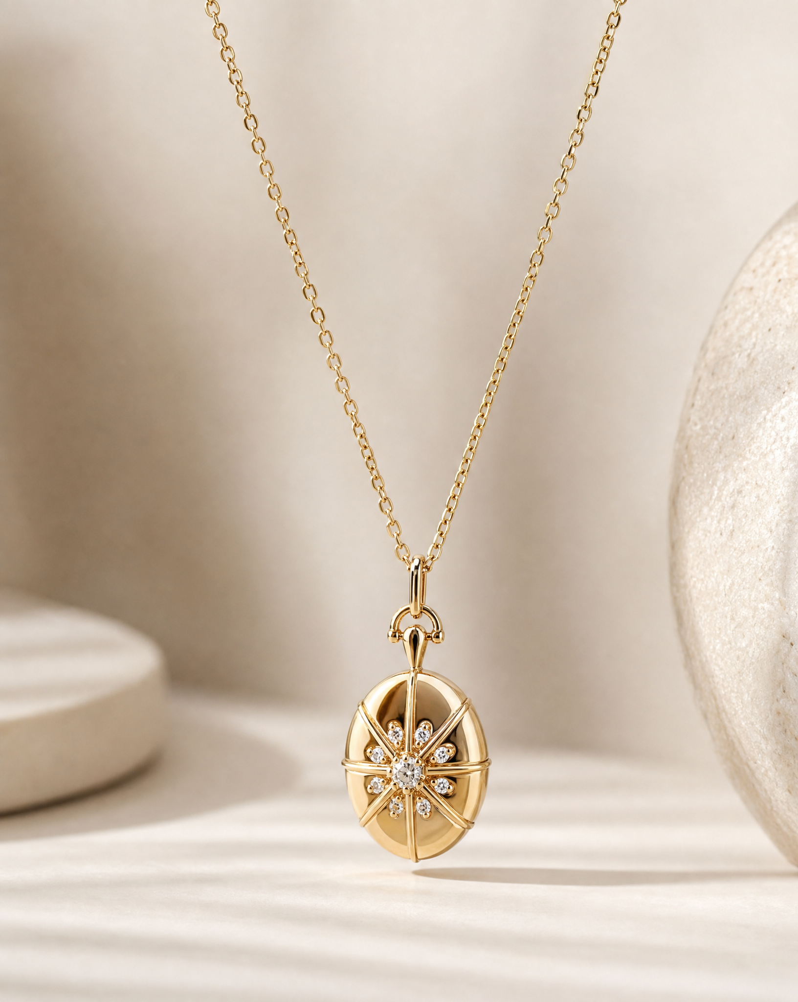 A gold pendant necklace featuring a compass rose design with a central cluster of small clear stones, displayed on a soft beige surface with a textured ceramic object in the background.