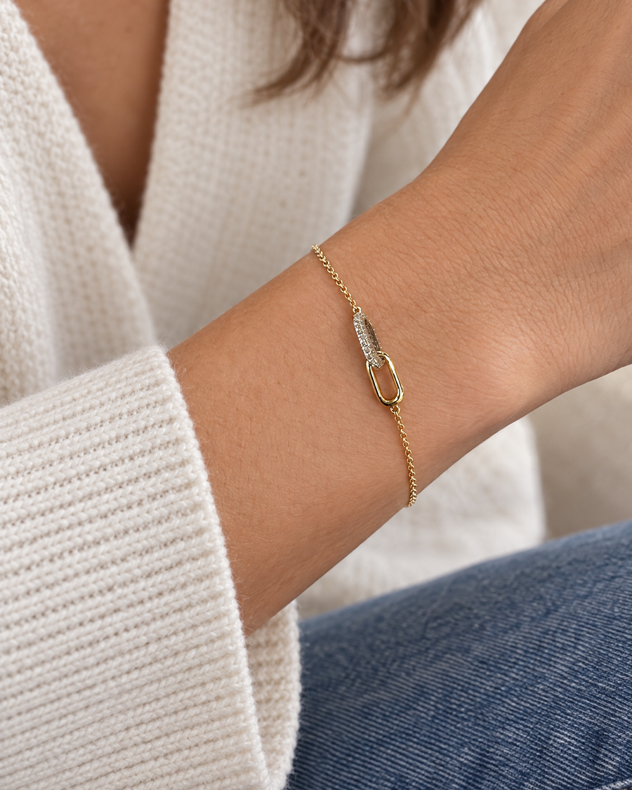 A delicate gold chain bracelet with a small pavé diamond accent and oval link detail, shown worn on a person's wrist.