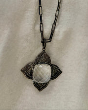 The MELISSA Silver Pendant Necklace by Dylan James showcases a large faceted Diamond Crystal in a decorative four-point frame on a textured 30" chain, elegantly set against a light fabric background.
