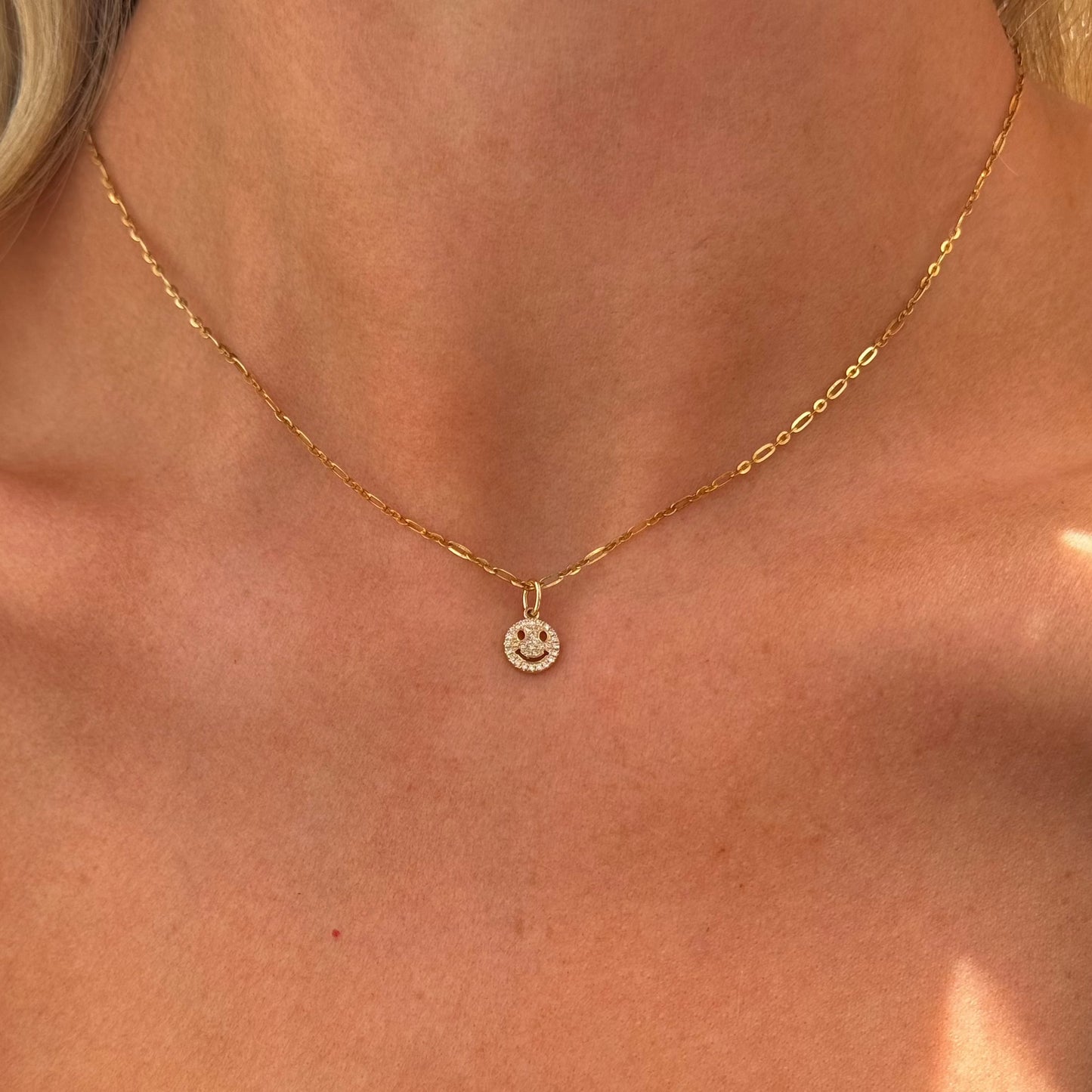 The SMILEY Diamond Necklace by Dylan James Jewelry is a 16" piece crafted in 14kt yellow gold, featuring a small round pendant encrusted with tiny diamonds, worn elegantly around one's neck.