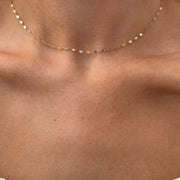 Close-up of a person wearing the elegant LIV Gold Chain by Dylan James Jewelry, a delicate 14kt yellow gold diamond cut chain necklace, against bare skin.