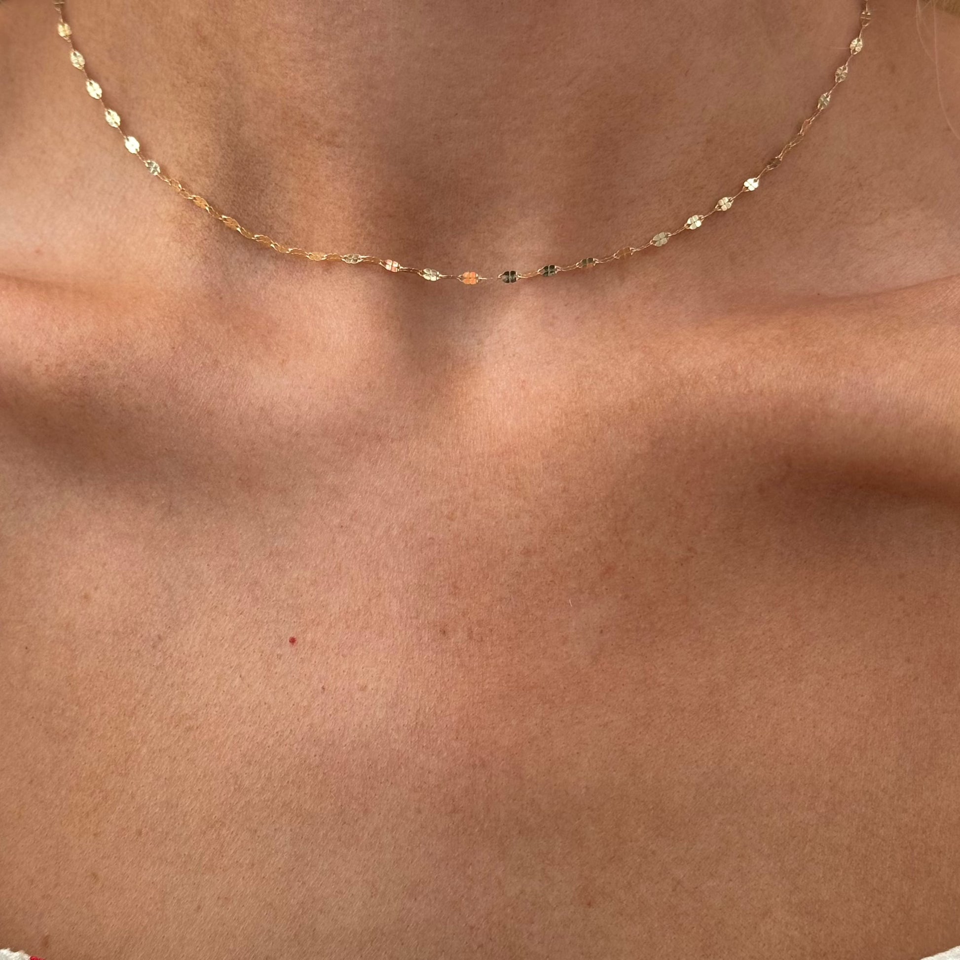 Close-up of a person wearing the elegant LIV Gold Chain by Dylan James Jewelry, a delicate 14kt yellow gold diamond cut chain necklace, against bare skin.